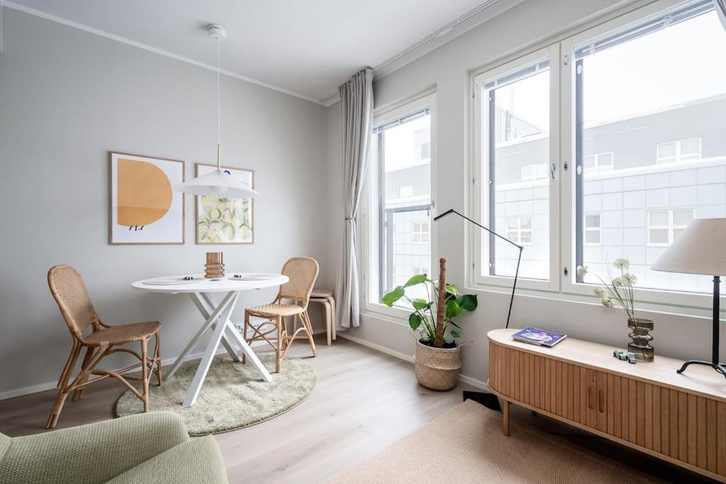 uma sala de estar com uma mesa, cadeiras e janelas em Kaunis ja toimiva uusi yksiö em Kuopio