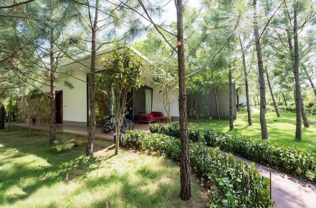 a house in the middle of a yard with trees at Villa R331 Forest Flamingo Dai Lai Resort in Phúc Yên