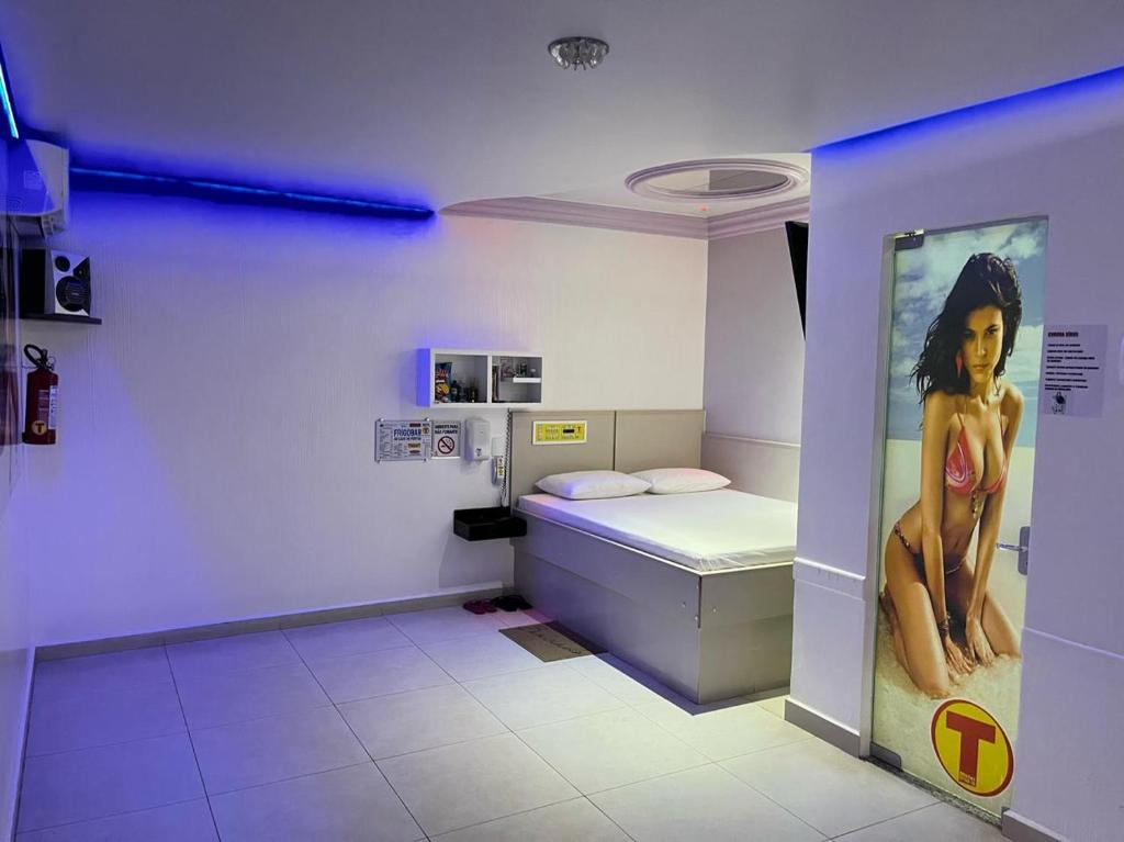 um quarto com uma cama com um poster de uma mulher em Motel Drive in T em Chapecó