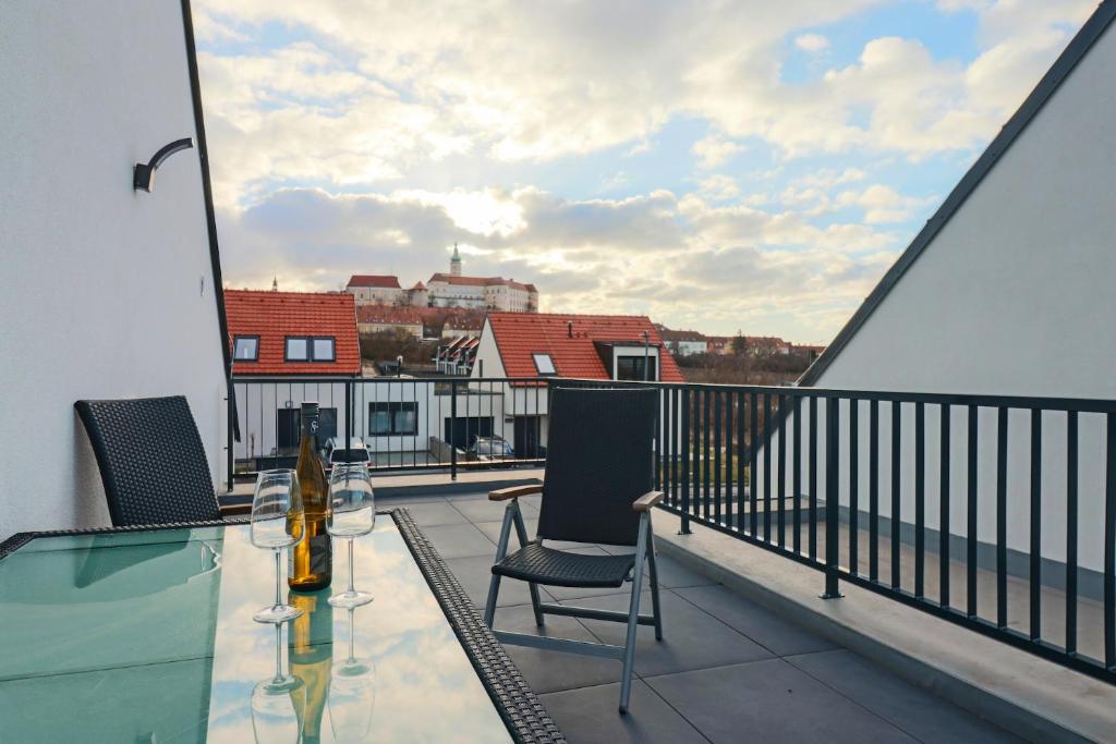 a balcony with a glass table and chairs on a balcony at Apartmány Mikulovské zahrady in Mikulov