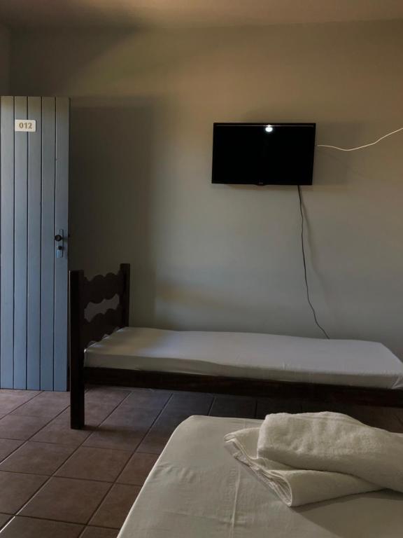 a room with a bed and a tv on the wall at Pousada Praia Do Farol in Alcobaça