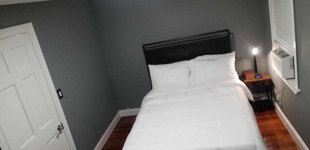 - une chambre avec un lit doté de draps et d'oreillers blancs dans l'établissement A comfy place in queens, à Cambria Heights