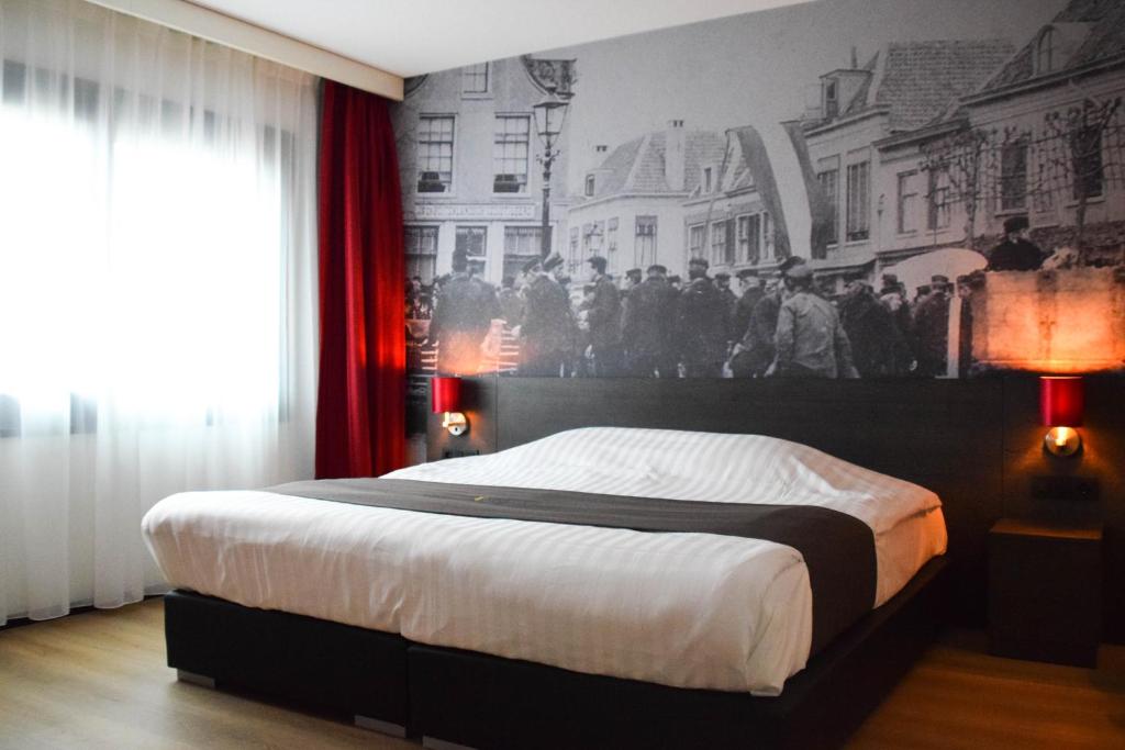 een slaapkamer met een groot bed met een muurschildering aan de muur bij Bastion Hotel Amersfoort in Amersfoort