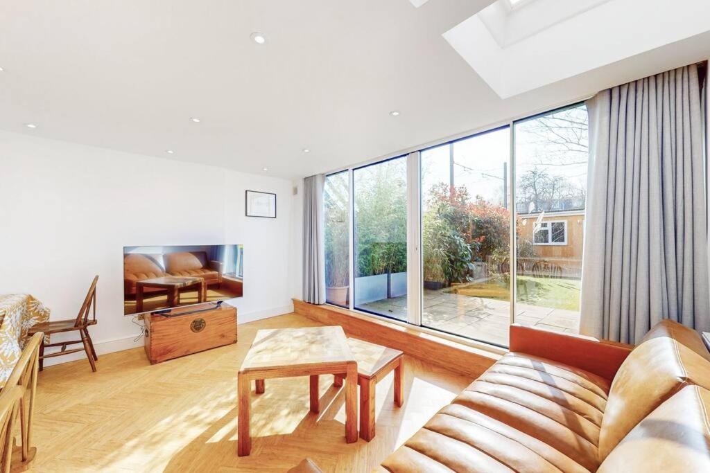 a living room with a couch and a large window at Cosy 2Bed garden flat in Wimbledon near the tube in London