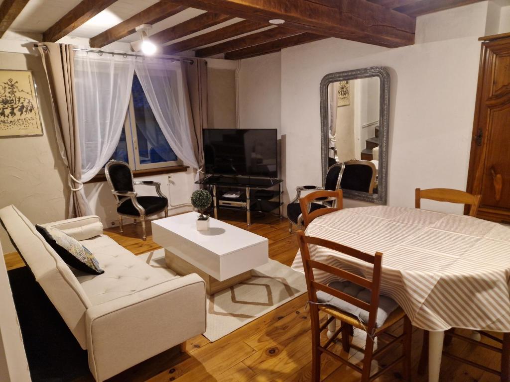 sala de estar con mesa, sillas y TV en Charmante petite grange - 5 Couchages en Nalzen