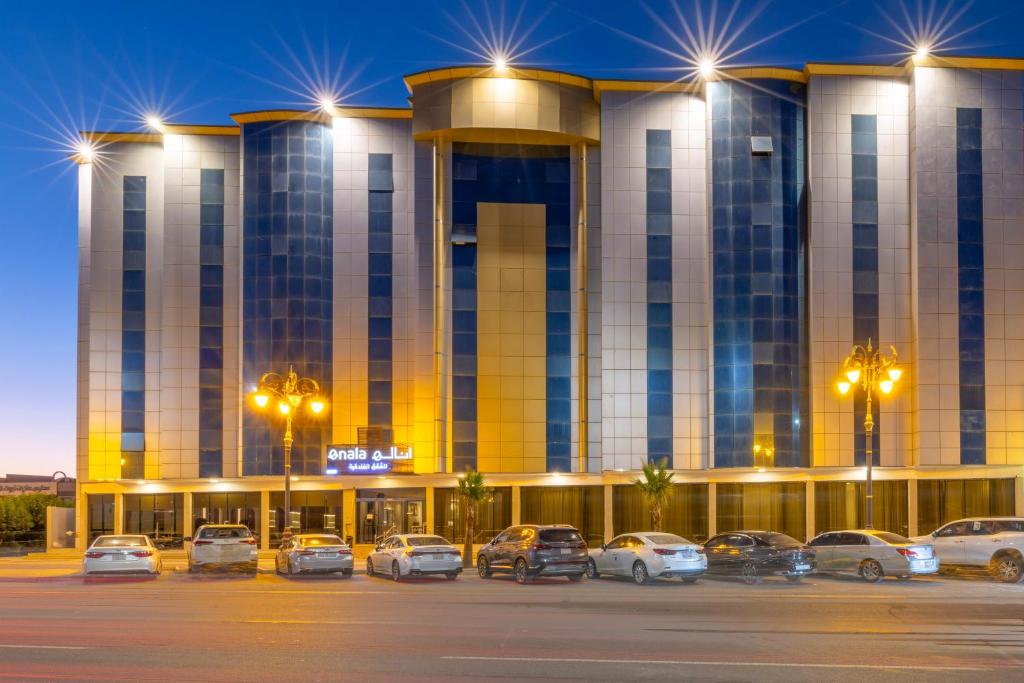 Enala Hotel - Tabuk في تبوك: مبنى كبير به سيارات تقف في موقف للسيارات