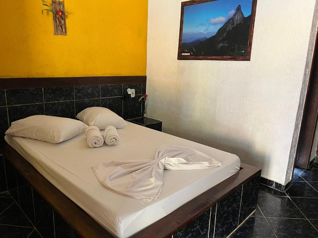 Una cama con dos toallas enrolladas. en Suíte serra dos órgãos guapimirim en Guapimirim
