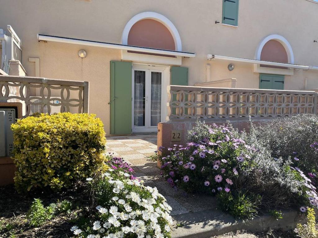 un bâtiment avec un bouquet de fleurs devant dans l'établissement Maison Climatisée à 2 Pas de la Plage avec Piscine et Parking Privé, 6 Couchages - Gruissan - FR-1-229-486, à Gruissan