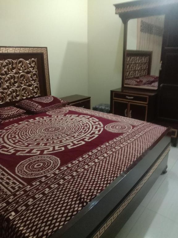 a bedroom with a bed with a red comforter at Gujrat Guest House in Gujrāt