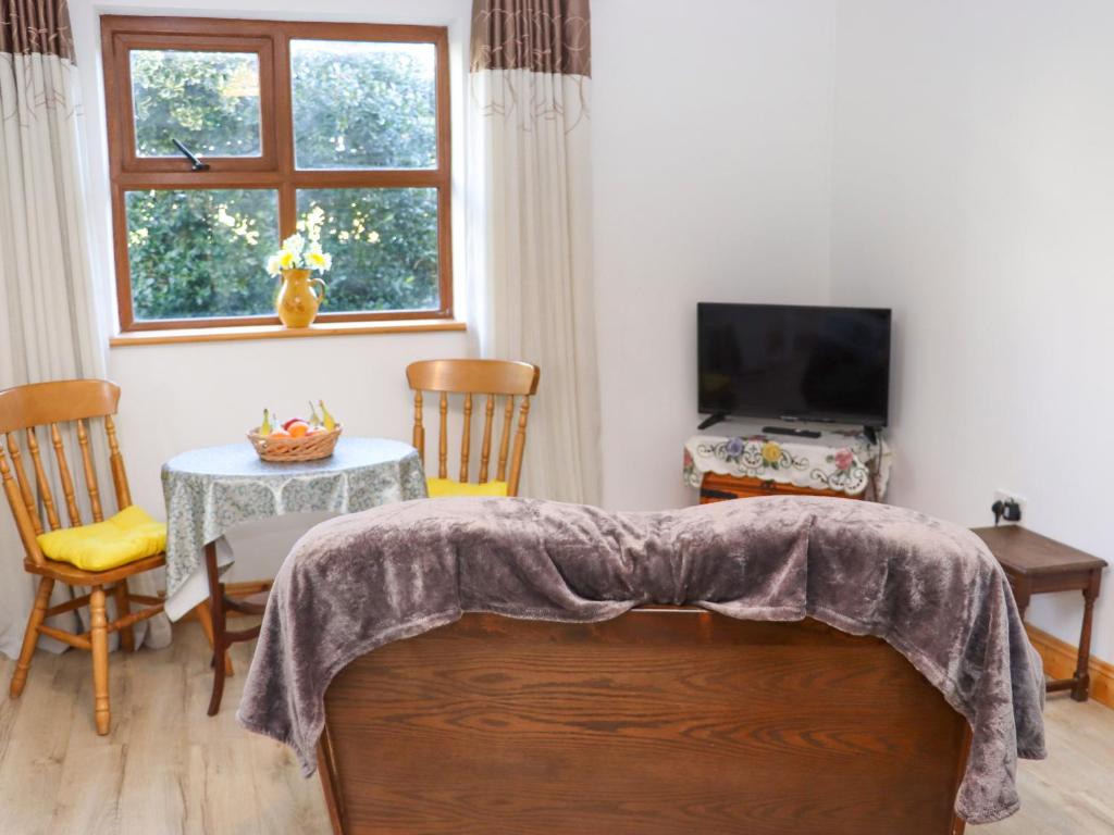 a living room with a bed and a table and a television at Wheatfield Lodge in Fethard on Sea