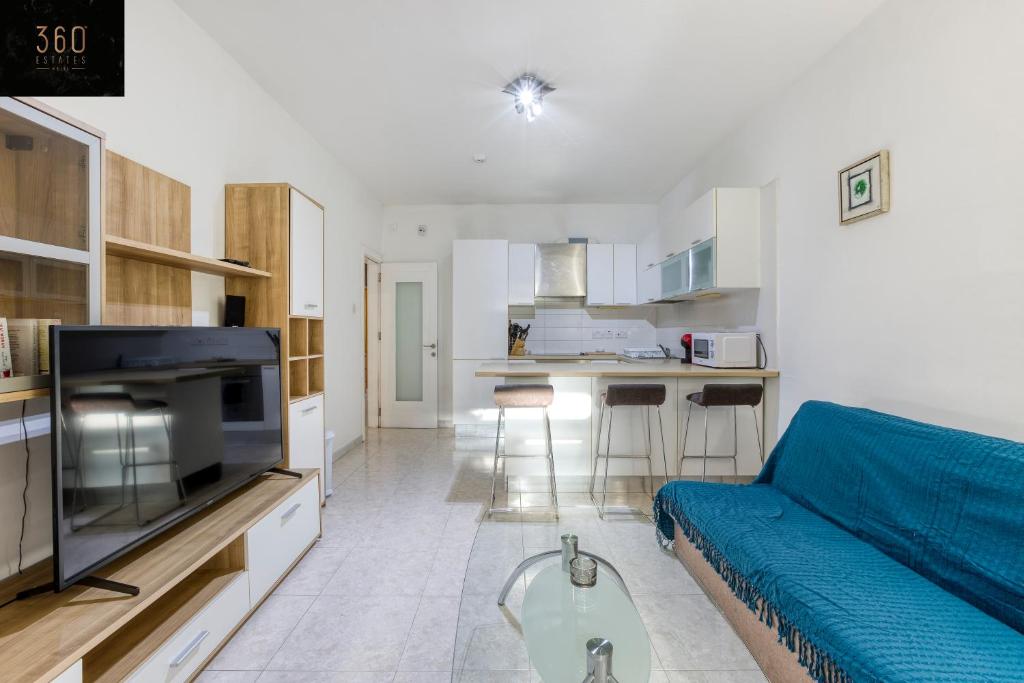 un soggiorno con divano blu e una cucina di Spacious, central APT in Paceville/St Julians by 360 Estates a San Giuliano