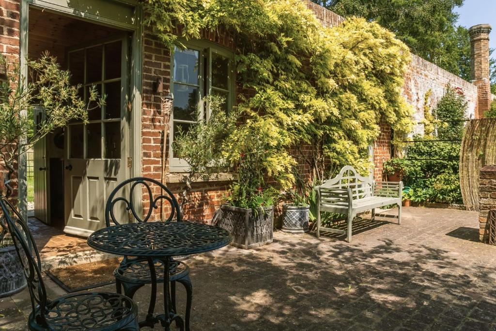 a patio with a table and chairs and a bench at The Little Potting Shed in Sedgeford