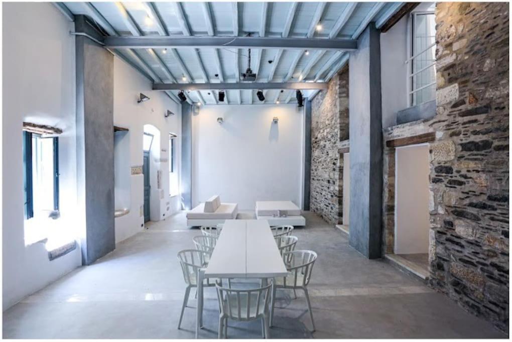 a room with tables and chairs and a brick wall at La Galerie - Art House Parikia in Parikia