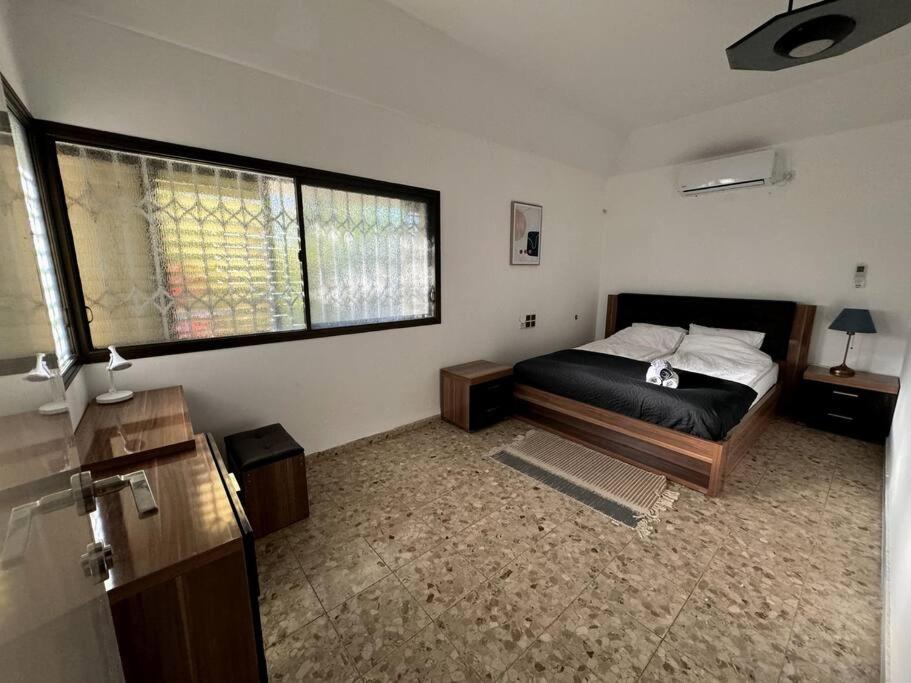 um quarto com uma cama e uma grande janela em Apartment with patio and parking em Nahariya