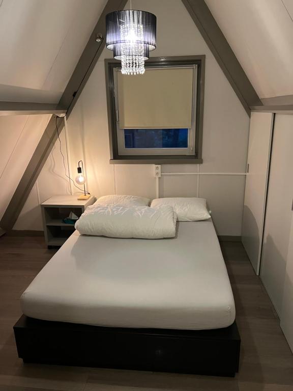 - une chambre avec un lit et un lustre dans l'établissement Dennenrust A-frame huisje middenin het bos., à Lanaken