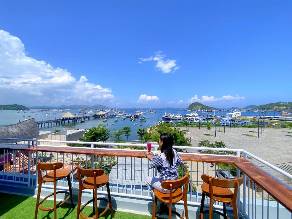 a woman sitting on a balcony with a drink at Flamingo Ceria in Labuan Bajo