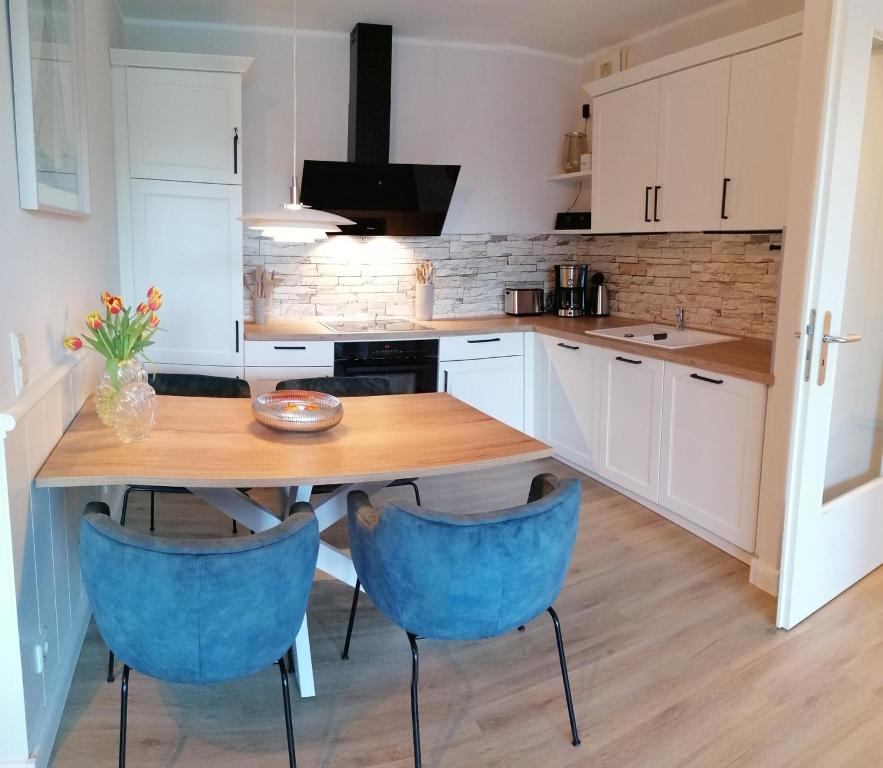 eine Küche mit einem Holztisch und blauen Stühlen in der Unterkunft Apartment 509 - FeWo in der Villa Kurpark in Zingst