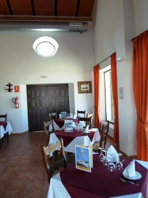 a dining room with tables and chairs with red curtains at Complejo Pueblo Blanco in Olvera