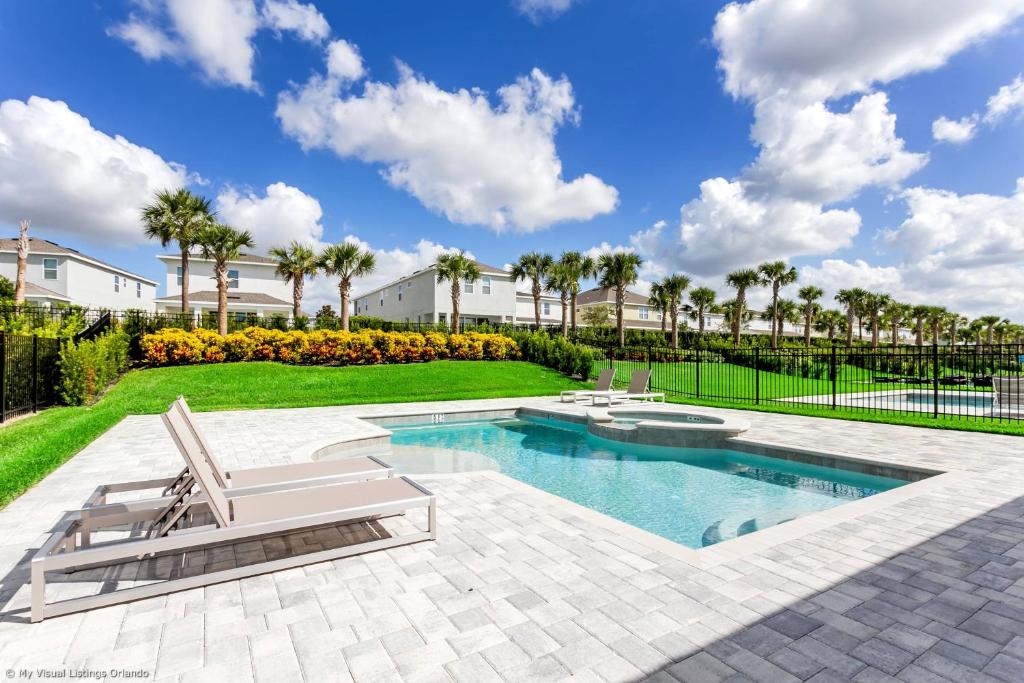 una piscina con 2 tumbonas y un patio con palmeras en Encore Resort 6 Bedroom Vacation Home with Pool 1913, en Orlando