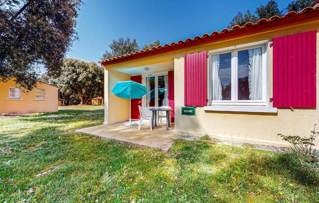 a small house with a table and a blue umbrella at Lovely Home In Saint-savinien With Outdoor Swimming Pool in Saint-Savinien