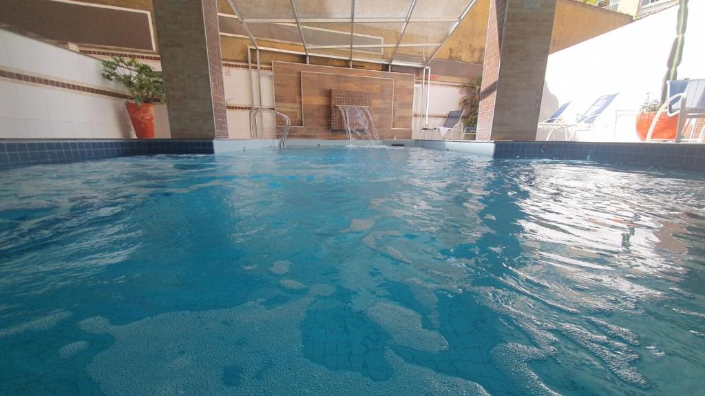 duży basen z niebieską wodą w budynku w obiekcie Presidente Hotel w mieście Poços de Caldas