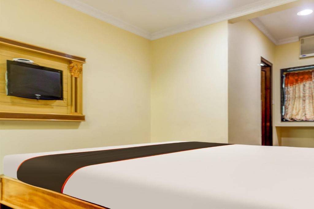 sypialnia z łóżkiem i telewizorem na ścianie w obiekcie Super Collection O Hotel Adithya Central w mieście Elūru