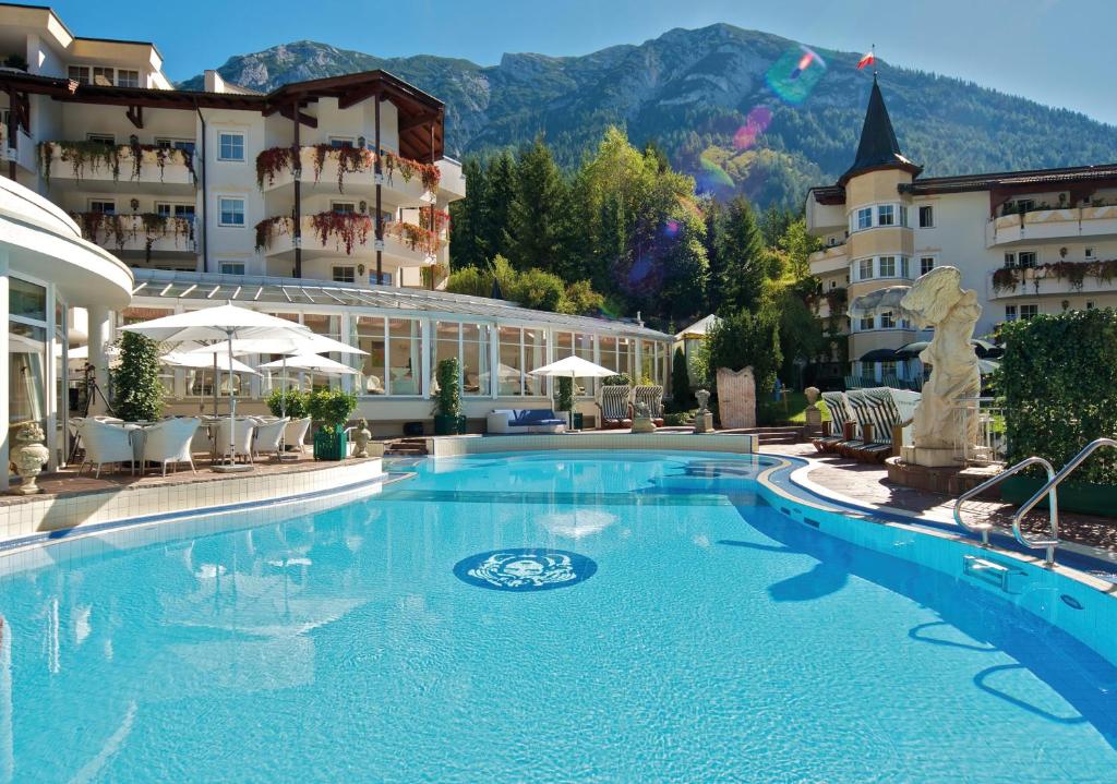a large swimming pool in front of a hotel at Posthotel Achenkirch Resort and Spa - Adults Only in Achenkirch