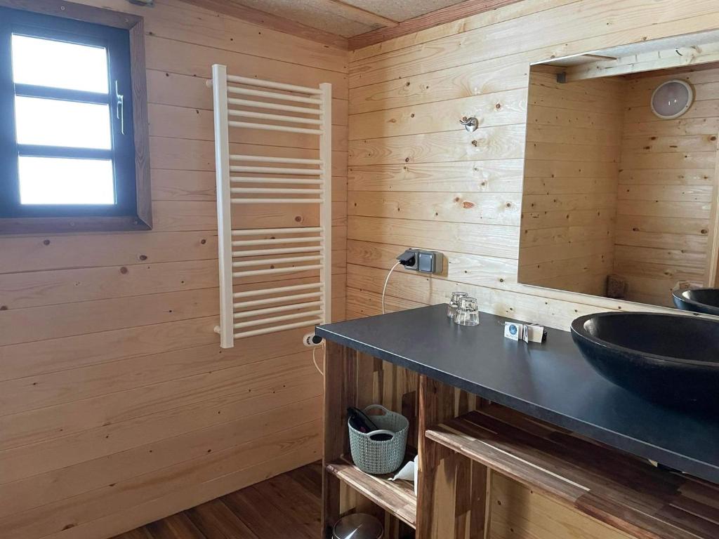 La salle de bains est pourvue d'un lavabo noir et de murs en bois. dans l'établissement KAZ INSOLITE, à Saint-Louis