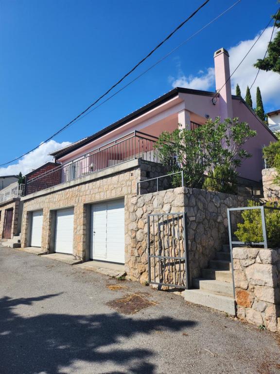 uma casa com três portas de garagem e uma parede de pedra em Guest House Karlobag - Villa Rose em Karlobag