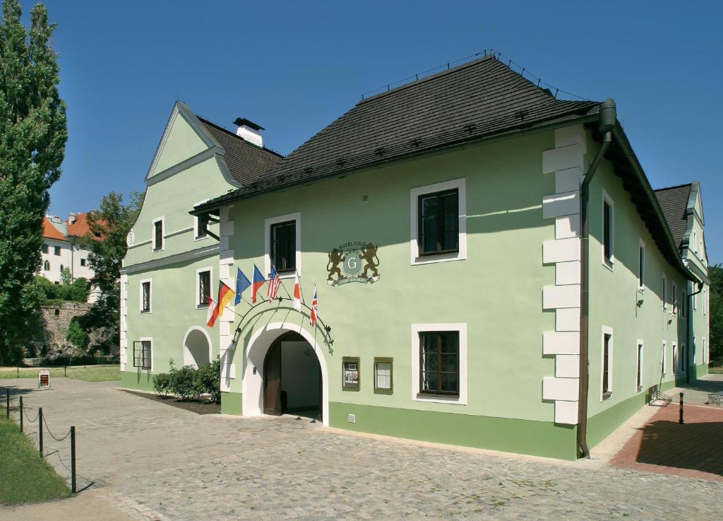 a large green building with an arch and flags at Gold in Český Krumlov