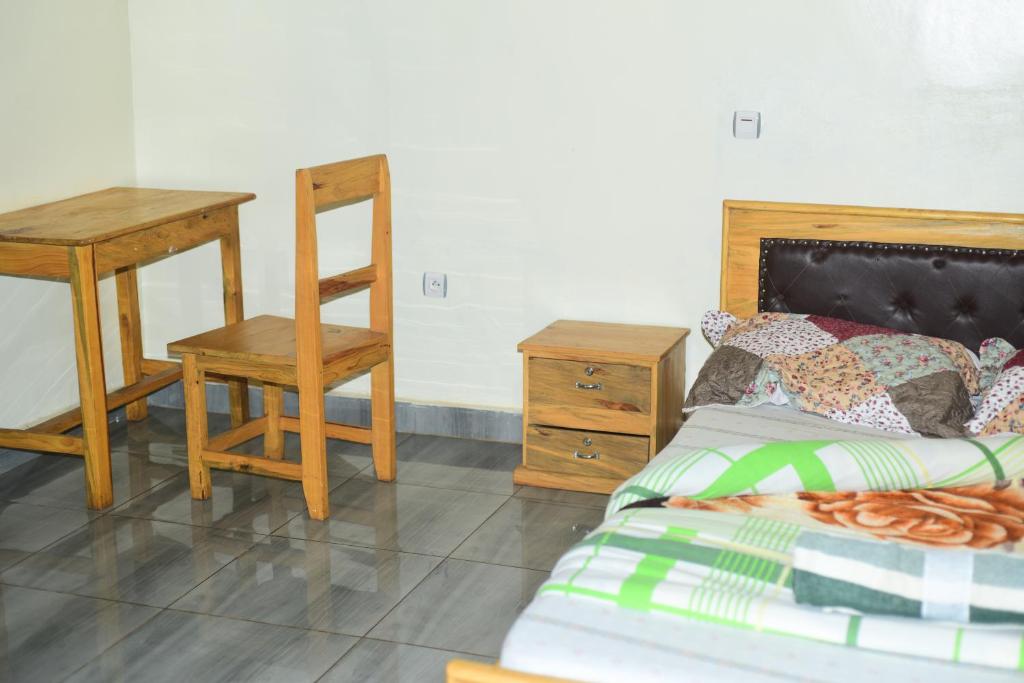 Schlafzimmer mit einem Bett, einem Schreibtisch und einem Stuhl in der Unterkunft Akagera Neighbors in Kabarondo