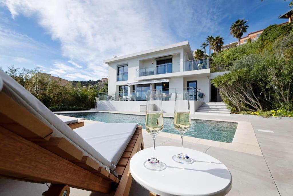 a couple of glasses of wine sitting on a table in front of a house at Sunnydaze, 4 bed V/F pool villa in Villefranche-sur-Mer