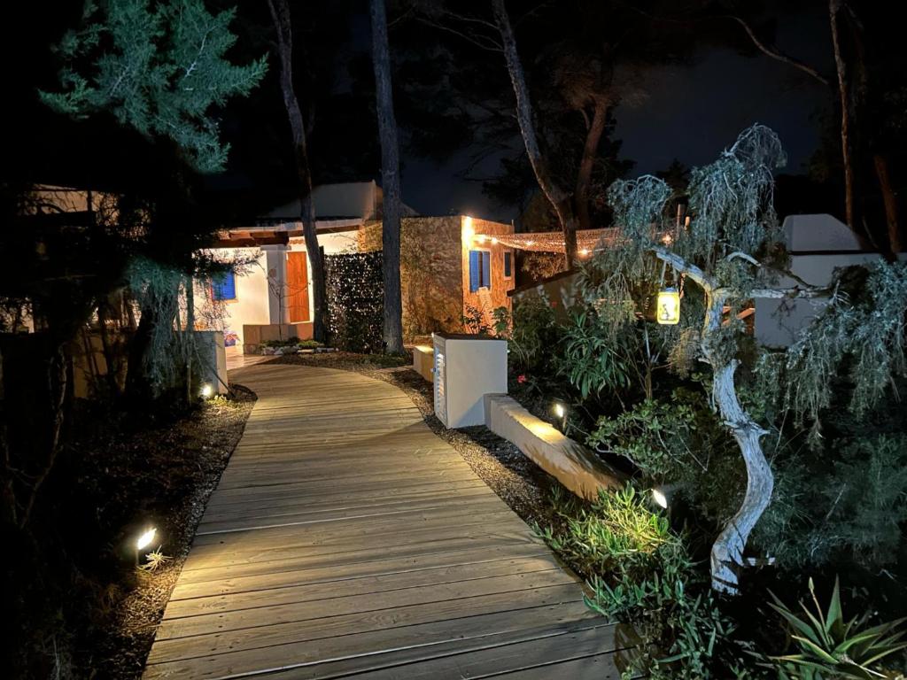 un camino de madera que conduce a una casa por la noche en Apartamento Sa Ginebra, Cala Saona en Cala Saona