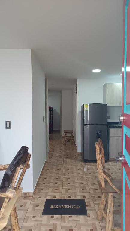 a room with a kitchen with a refrigerator and chairs at APARTAMENTO TURISTICO SALENTO QUINDIO R. in Salento