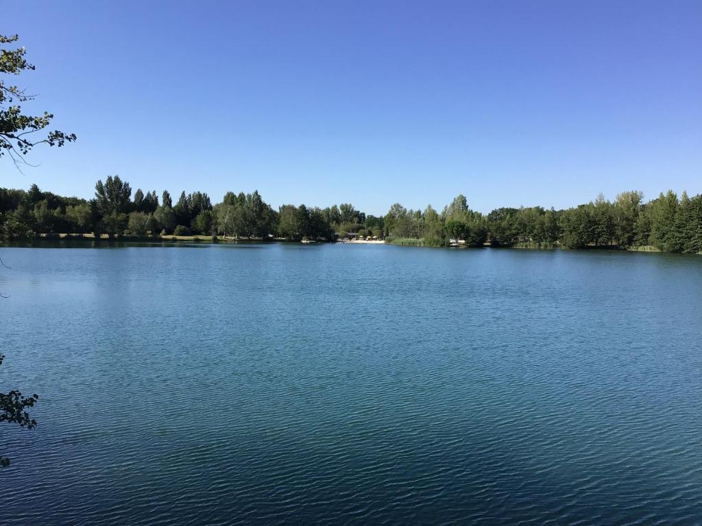 un gran lago azul con árboles en el fondo en Les Trois Chênes, en Sainte-Gemme