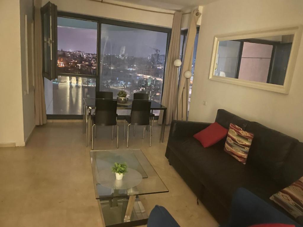 sala de estar con sofá negro y mesa de cristal en מגדלי המרינה, en Herzliya