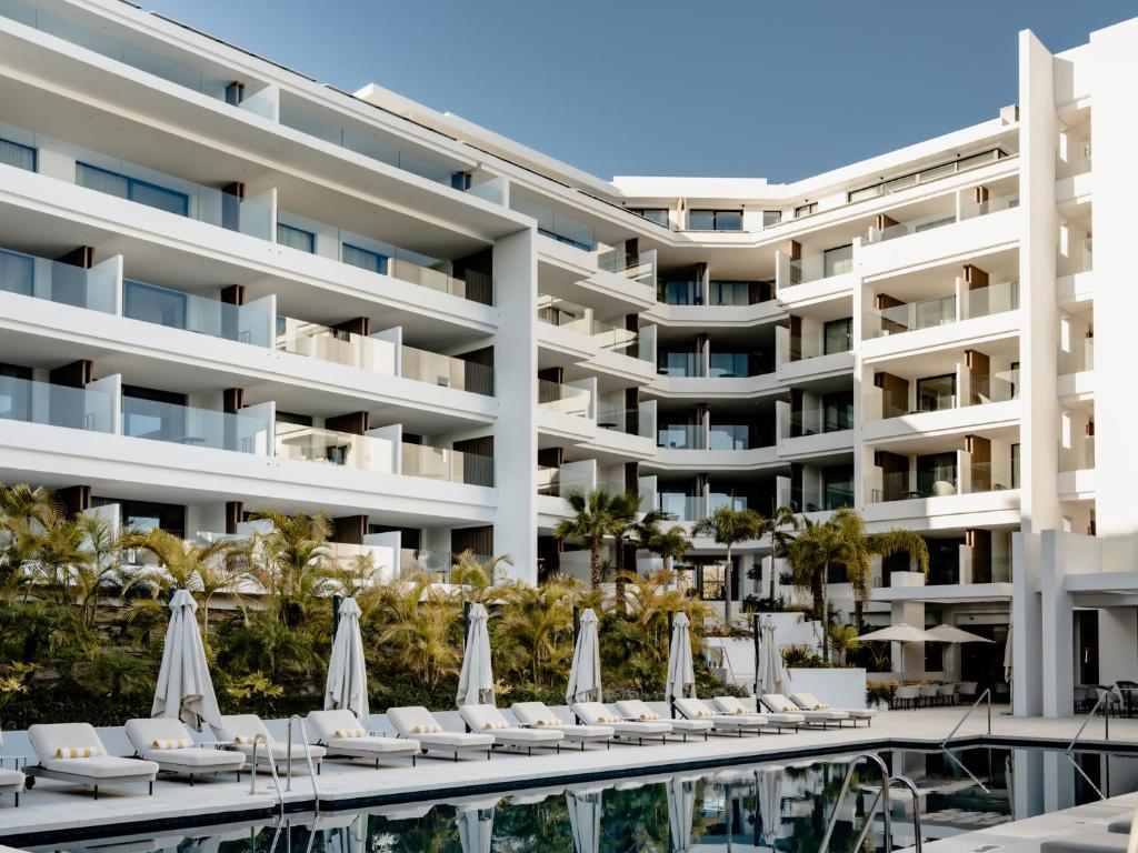 una vista exterior de un hotel con sillas y sombrillas en THE FLAG Costa del Sol Marbella, Estepona, en Estepona