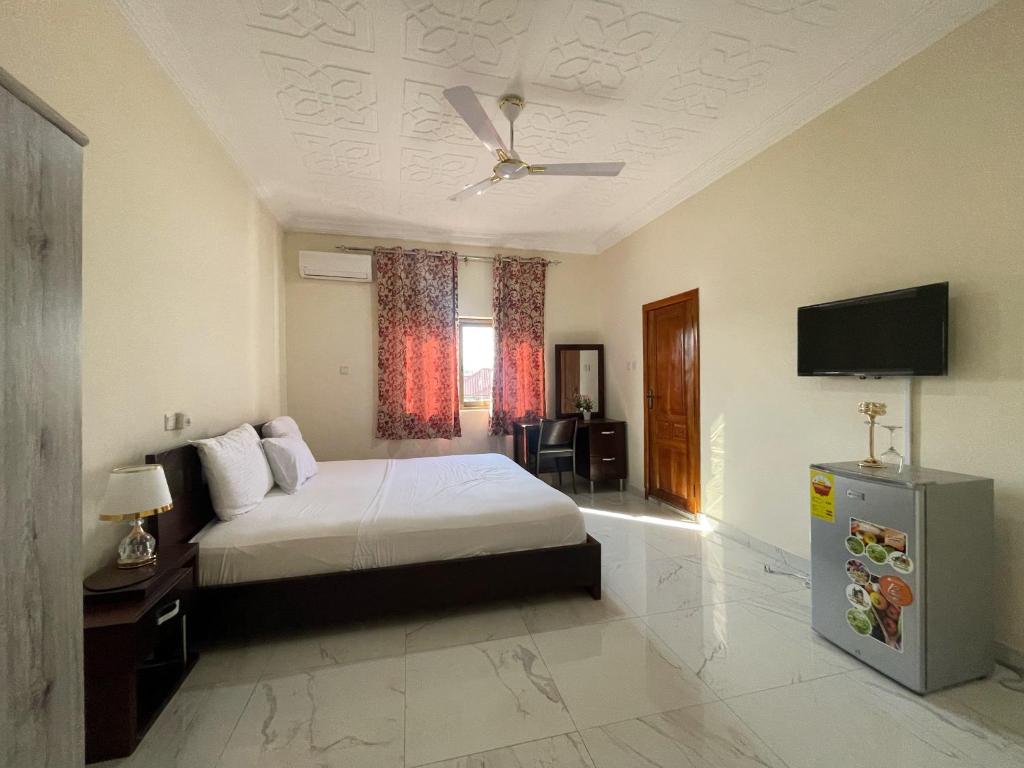 een slaapkamer met een bed en een flatscreen-tv bij JD Hotel And Bar. in Accra