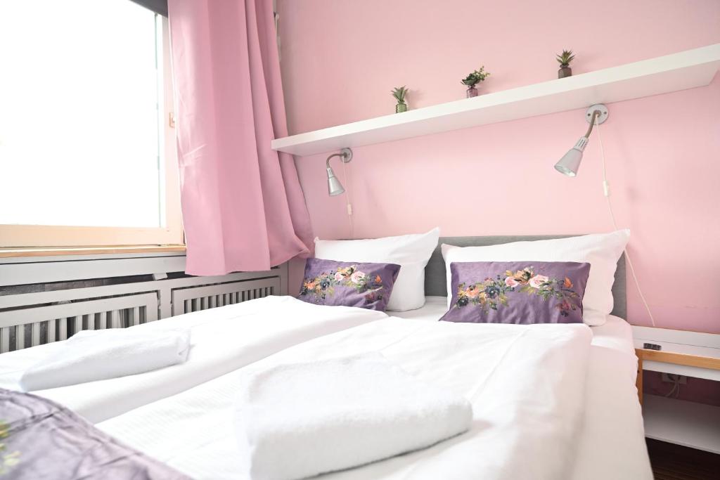 - 2 lits dans une chambre aux murs roses dans l'établissement Self check in City HoStel Nordstern, à Essen
