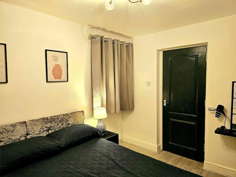 a bedroom with a black bed and a black door at Modern & Cosy 1 bedroom flat in Bridgend