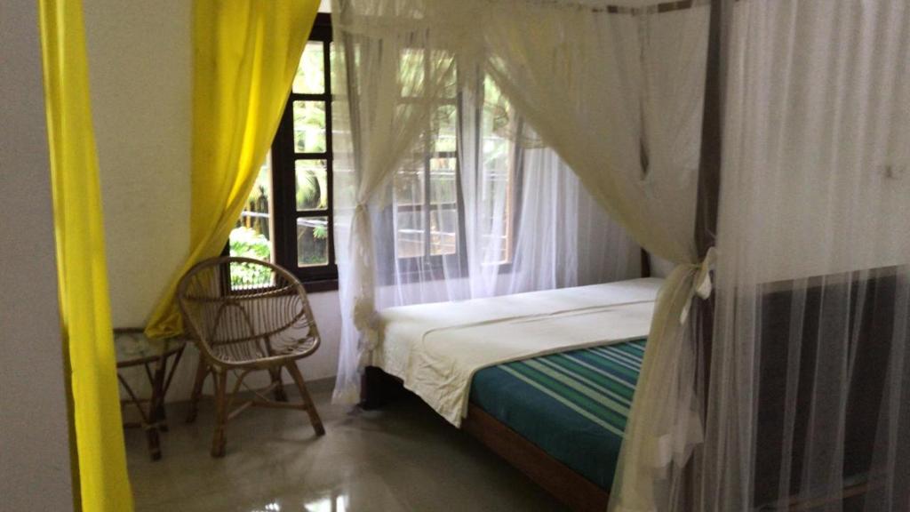 a bedroom with a canopy bed and a window at HAPPY REST in Unawatuna