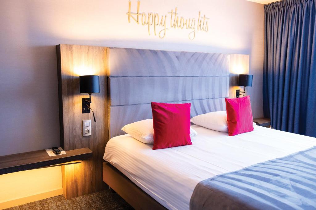 een hotelkamer met een bed met twee roze kussens bij Van der Valk Hotel Liège Congres in Luik