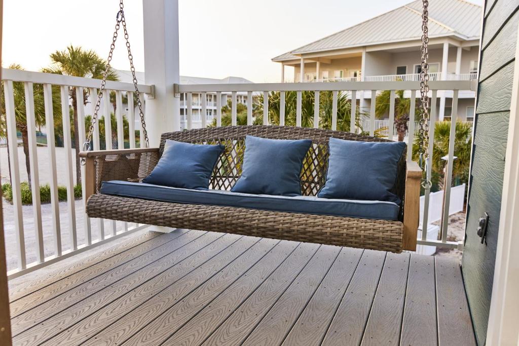 eine Korbschaukel auf einer Veranda mit blauen Kissen in der Unterkunft Summer Breeze D212 - Bungalow 6 in Destin