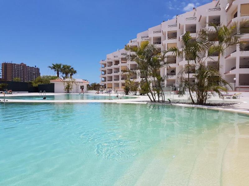 a large pool of water in front of a building at Los Cristianos, Tenerife in El Guincho