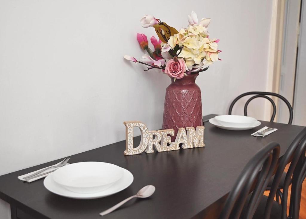 una mesa con platos y un jarrón con flores. en Vintage Dream Apartment, en Oradea