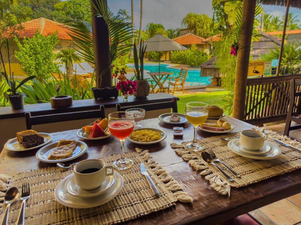 a table with plates of food and drinks on it at Pousada Berro do Jeguy in Pipa
