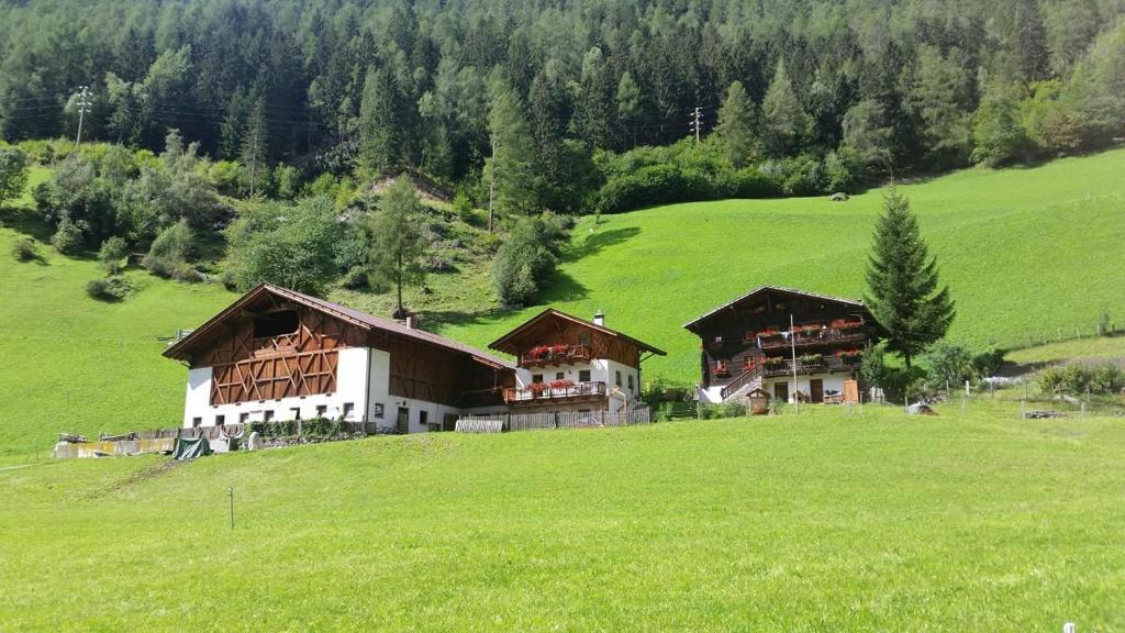 a large house on a green hill in a field at Ausser Brugghof in Senales