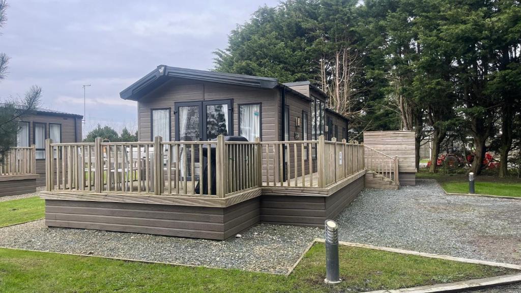 een kleine hut met een veranda en een hek bij Cosy 3-Bed hot tub Lodge in Pr3 in Preston