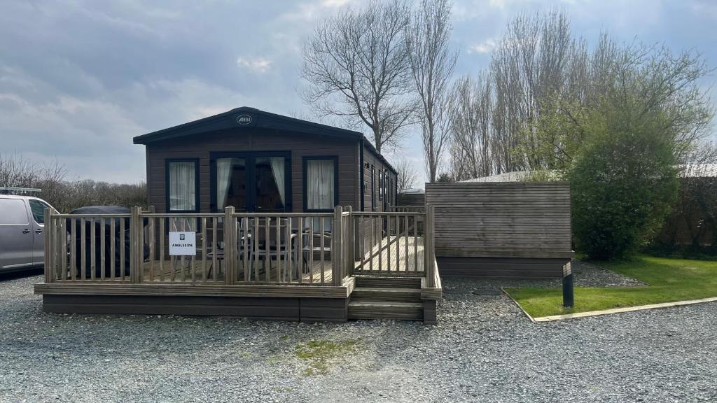 eine kleine Hütte mit einer Veranda und einem Zaun in der Unterkunft Immaculate 3-Bed Lodge in Out Rawcliffe in Great Eccleston