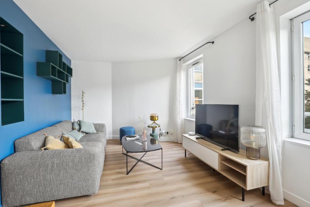 a living room with a couch and a tv at Appartement elegant- Parc Saint Cloud in Sèvres